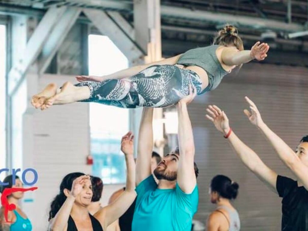 a group of people in a dance studio holding one person in the air