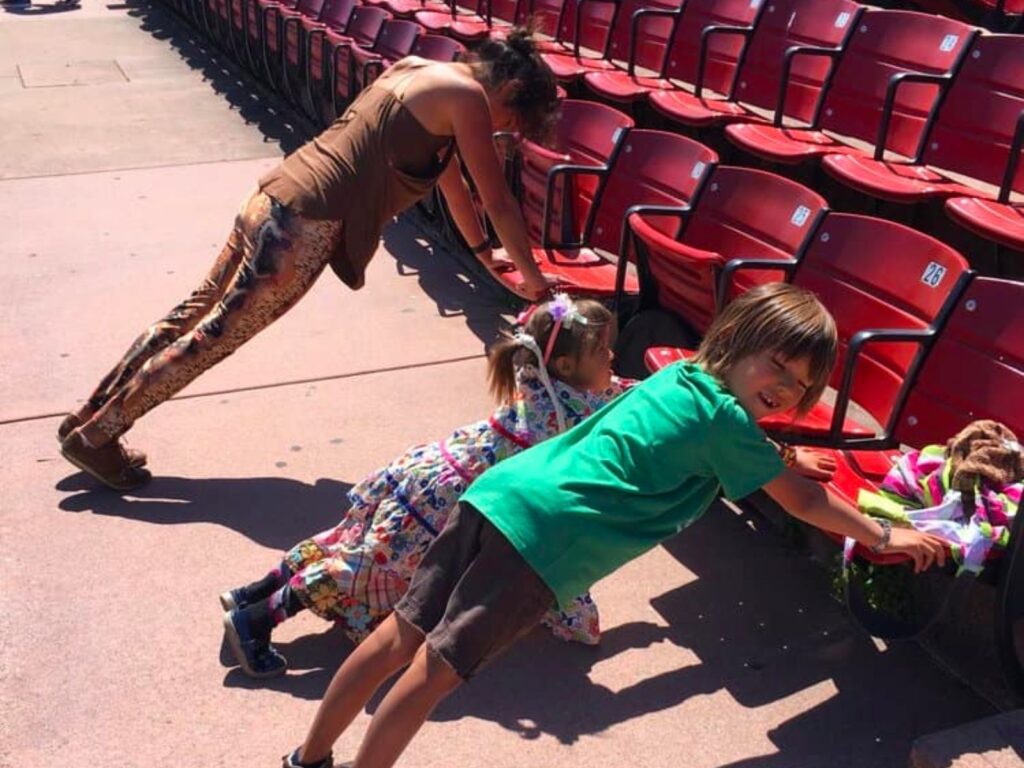 a person and two children doing planks on theater benches.