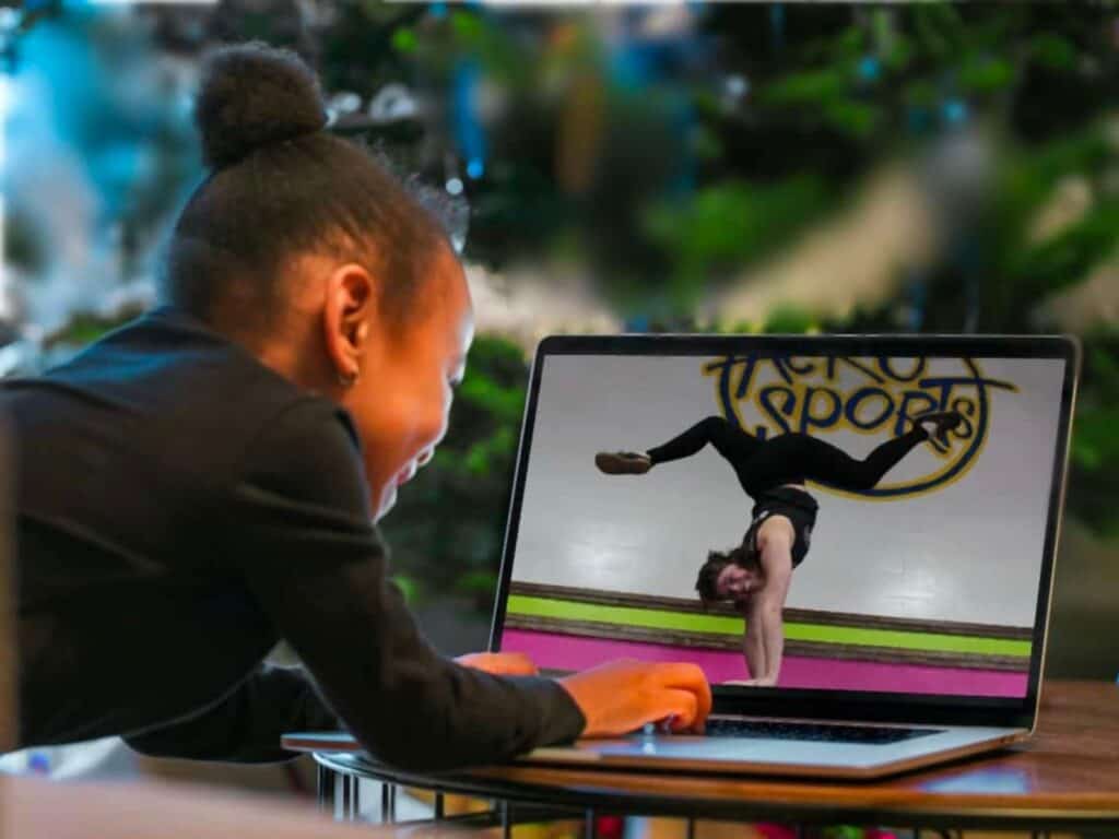 a person sitting in front of a laptop with a dance video playing on it